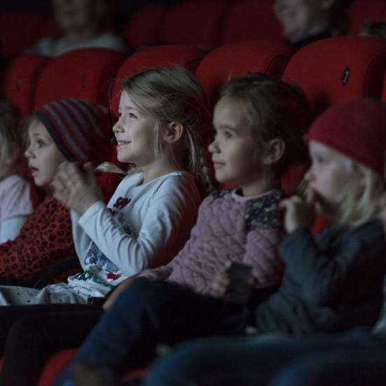 Glad børn sidder i biografmørket