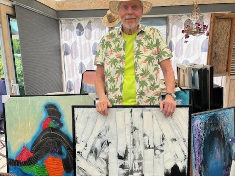 John Elsfort med tre af sine malerier