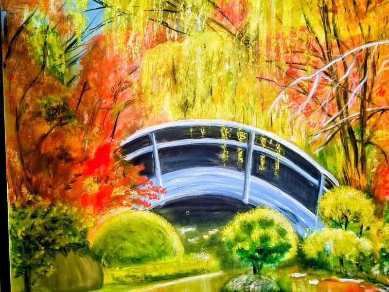 Buet bro over still vand omgivet af natur i efterårsfarver.