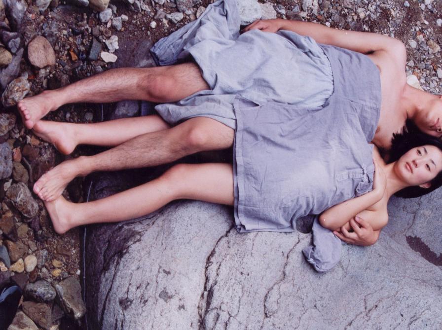 mand og kvinde ligger på stranden ved siden af hinanden, under et tæppe