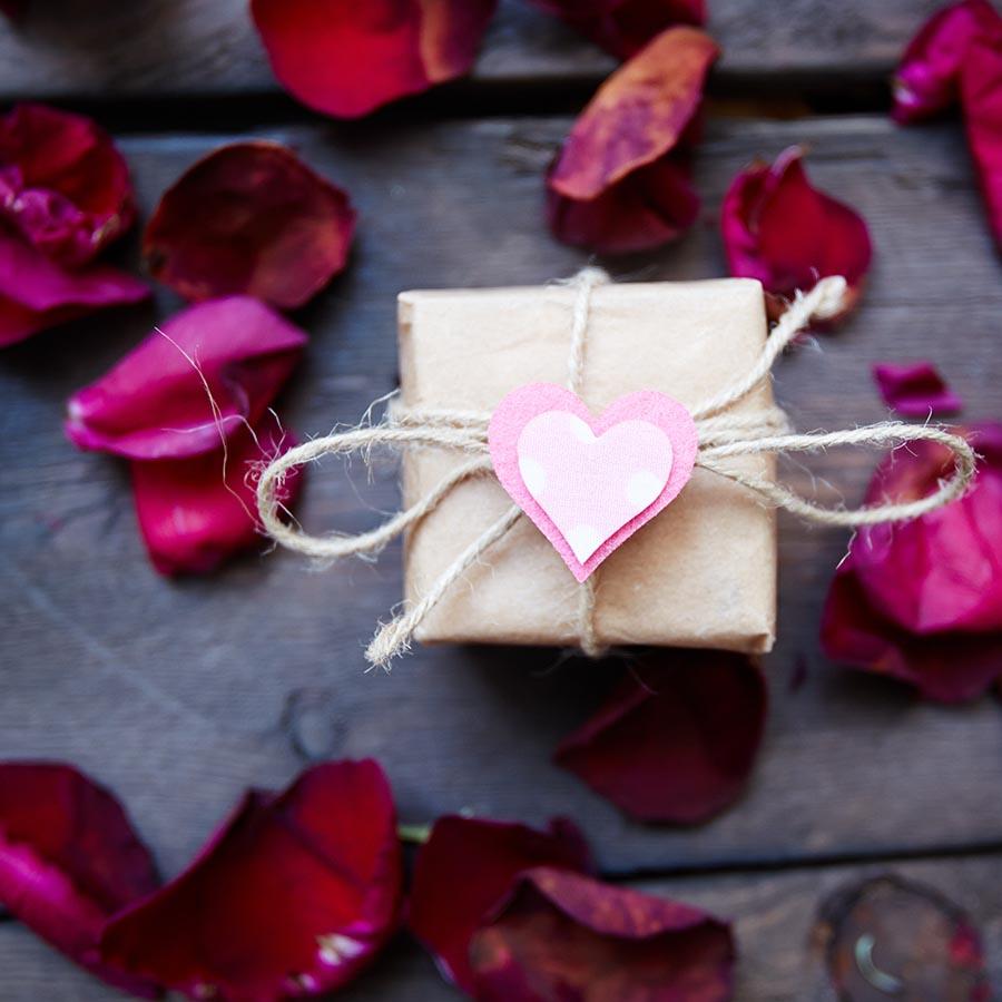 Foto af rosenblade og en lille gave med et hjerte på